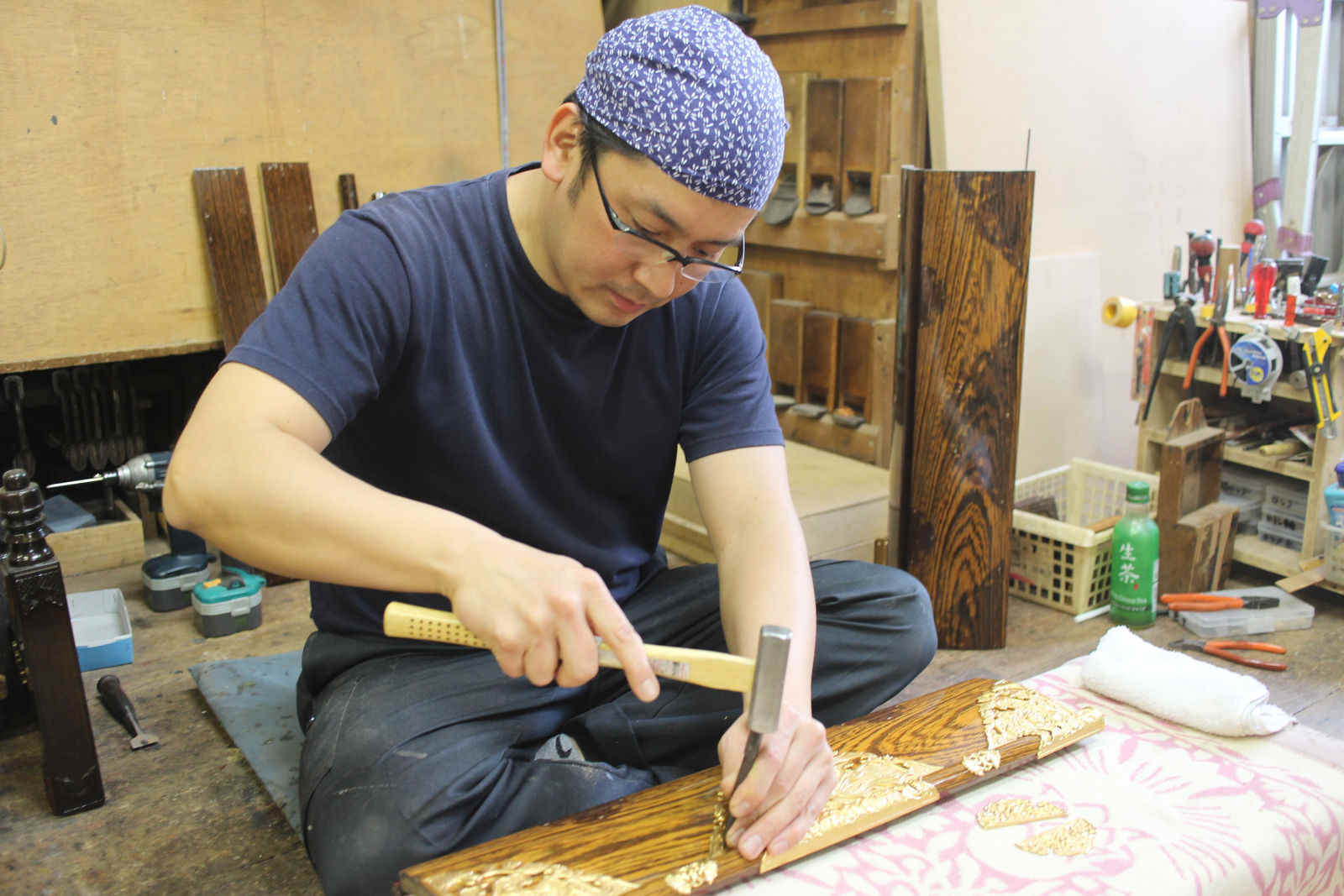 小づちで金の荘厳を打ち込む職人