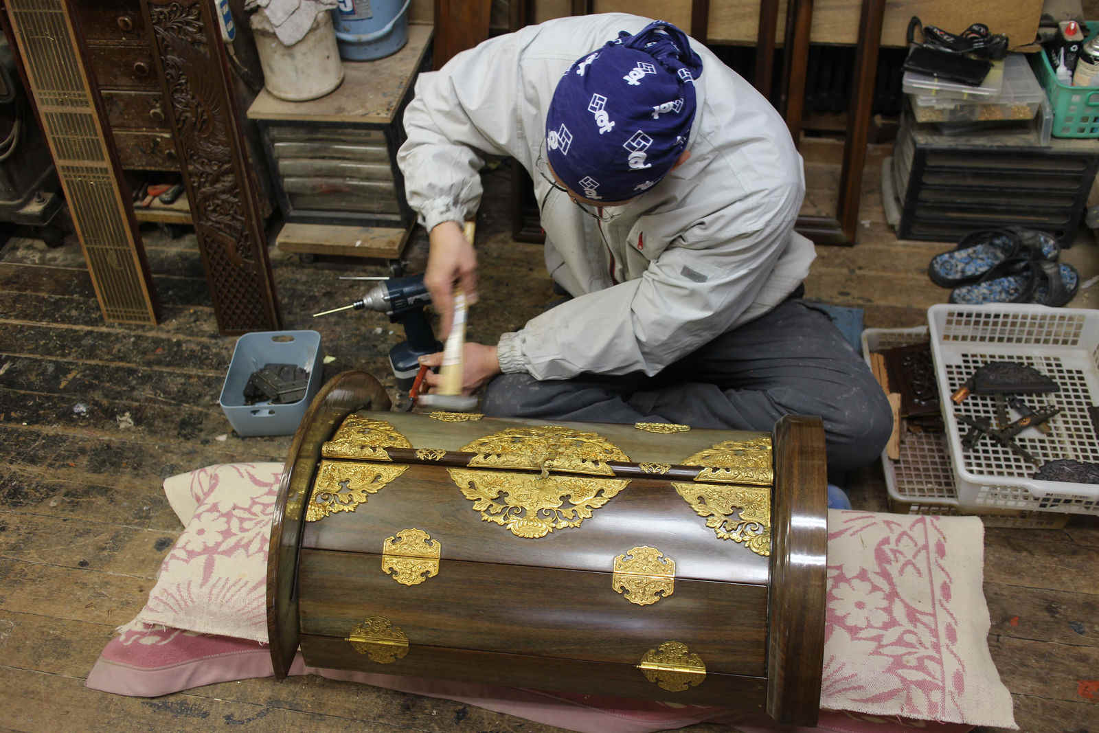 円筒形の厨子に金の金具を打ち込む